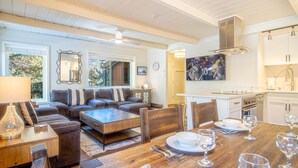 A modern living room with a sofa set, wooden coffee table, and dining table set for six. - Atelier Allure - 2BD Mountain View + Free Resort Amenities (Sun Valley)