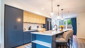 A modern kitchen with dark cabinets, a central island, and pendant lighting. - Mountain View Villa - Lux 3BD W/roof Terrace - Downtown Hailey (Hailey)