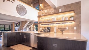 A modern kitchen with dark wood cabinets, a large island, and a built-in wine rack. - Panoramic Views! Designer`s Condo on Golf Course W/resort Amenities (Sun Valley)