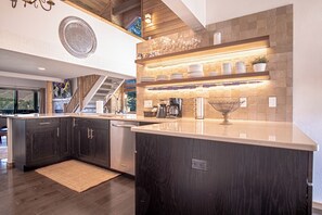 A modern kitchen with dark wood cabinets, a large island, and a built-in wine rack. - Panoramic Views! Designer`s Condo on Golf Course W/resort Amenities (Sun Valley)