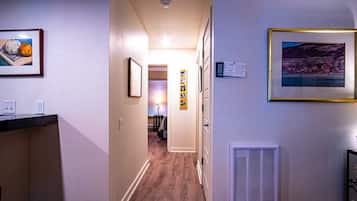 Un pasillo con piso de madera, una puerta al final y cuadros en las paredes.