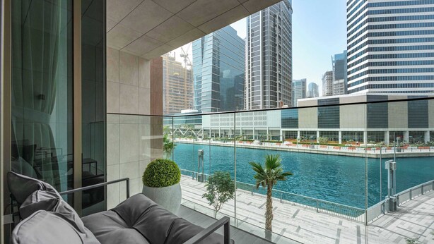 A modern hotel room with a balcony overlooking a water body and cityscape. - StayShort - Canal View 2BR in the Heart of Business Bay - Sleeps 6! (Business Bay)