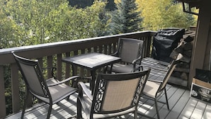 A covered outdoor seating area with a table and chairs, overlooking a forested valley. - Sv120 - Walk to Lifts & Town - Hot Tub & Pool (Ketchum)