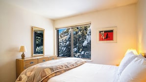 A bedroom with a bed, a dresser, a window with a view of trees, and a framed picture on the wall. - Sv120 - Walk to Lifts & Town - Hot Tub & Pool (Ketchum)