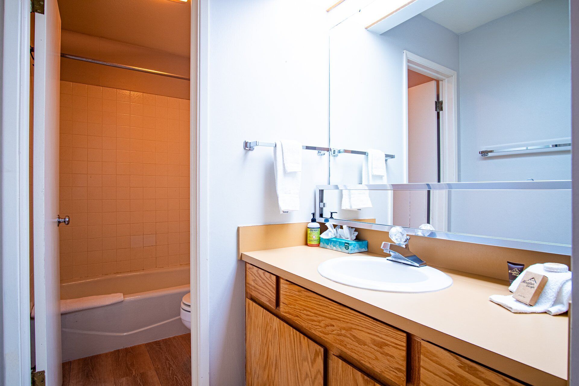 A bathroom with a white sink, wooden cabinets, a mirror, and a shower area.