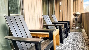 Eine Reihe Adirondack-Stühle mit Holztischen, ein gemustertes Parkett und eine Holzwand mit einem Fenster.