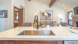 A kitchen with a large island, stainless steel sink, and modern lighting fixtures. - Skiway Chalet - Next to Warm Springs Lifts - Close to Natural Hot Springs (Ketchum)