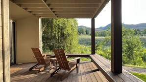A covered outdoor area with wooden furniture and a view of a green landscape. - Indian Springs Oasis - Near Ski Slopes & Resort Amenities (Sun Valley)