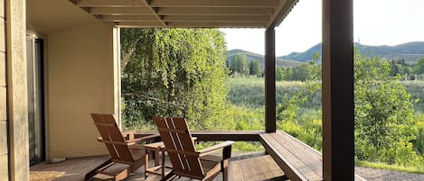 Un'area esterna riparata con mobili in legno e vista su un paesaggio verde.