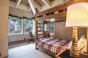 A cozy bedroom with a bunk bed, a desk, and a chair. There are large windows providing natural light and views of the outdoors. - Next to Warm Springs Lifts-hot Tub, Pool & Tennis! (Ketchum)