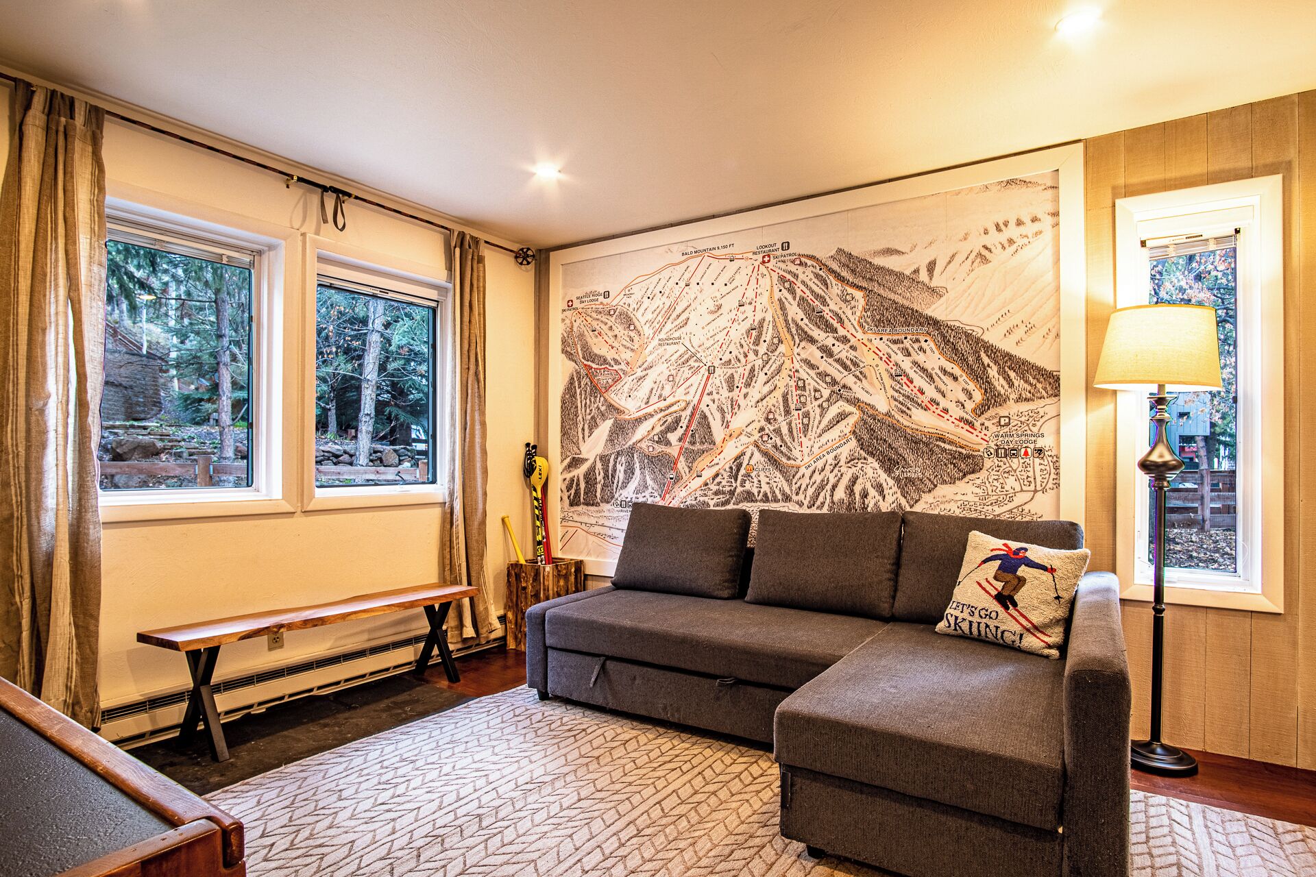 A cozy room with a large mountain-themed wall mural, a sofa, a bench, and a table.