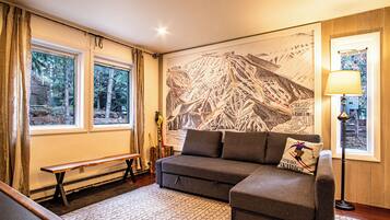 A cozy room with a large mountain-themed wall mural, a sofa, a bench, and a table.