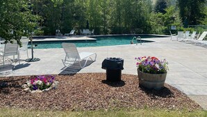 Piscina com espreguiçadeiras e um canteiro de flores.