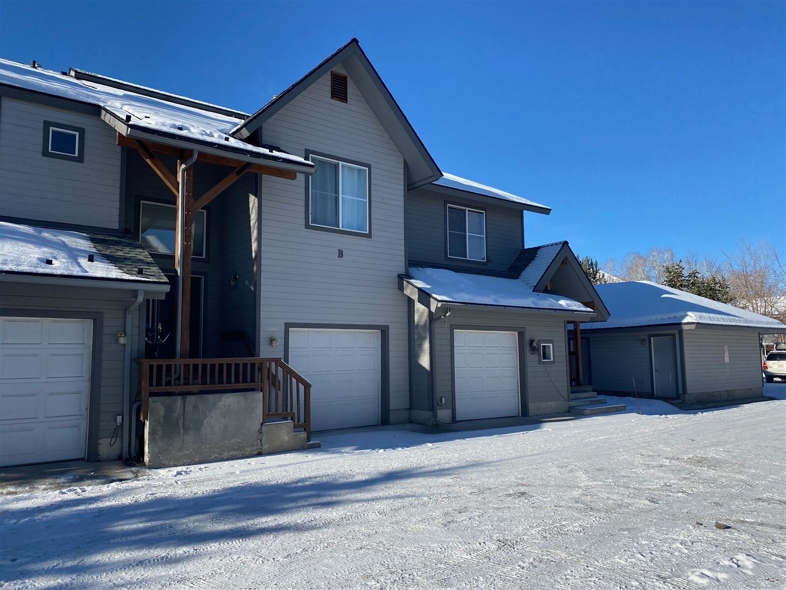A two-story house with a garage, a covered porch, and a snow-covered driveway.