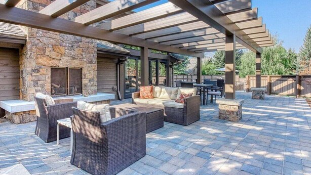 An outdoor patio with wicker furniture, stone walls, and a pergola. - Snow Creek 1554 - Ski-in/ski-out + Pool & Hot Tub (Sun Valley)