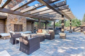 An outdoor patio with wicker furniture, stone walls, and a pergola. - Snow Creek 1554 - Ski-in/ski-out + Pool & Hot Tub (Sun Valley)