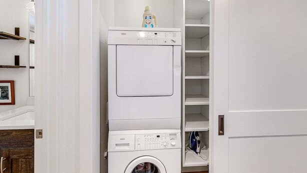 A laundry room with stacked appliances, including a dryer and a washing machine, and a shelf with a bottle on top. - West Ketchum Condo - Near Downtown & Sun Valley ski Lifts (Ketchum)