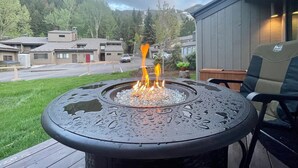 Eine Terrasse mit Feuerstelle, einem Stuhl und Blick auf eine Wohngegend mit Häusern und einer Straße.