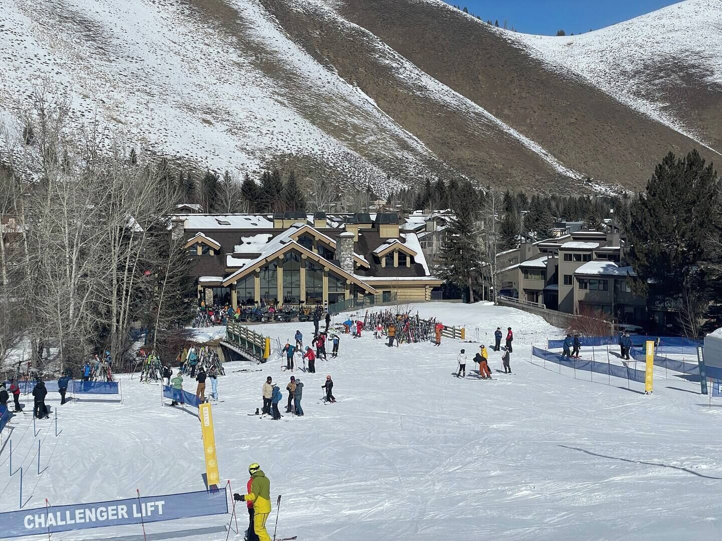 Ein Skigebiet mit einem großen Gebäude, einer Seilbahn und einem verschneiten Berggrund.