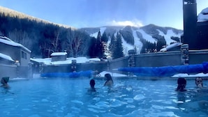 Ein Thermalgebiet mit einem Pool, umgeben von schneebedeckten Bergen und Bäumen.