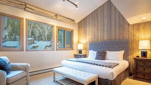 Ein Schlafzimmer mit einem großen Bett, einer Bank, einem Sessel und einem Nachttisch.
