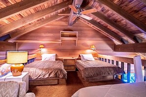 A cozy attic bedroom with wooden beams, two beds, nightstands, lamps, and a ceiling fan. - Snow Creek 1553 - Ski-in/ski-out + Pool & Hot Tub (Sun Valley)