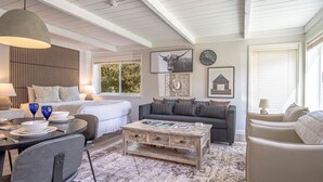 A cozy living room with a large window, a dining area with a table set for two, and a comfortable seating arrangement. - Atelier Escape - Sun Valley Studio + Resort Amenities (Sun Valley)