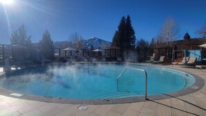A pool area with a clear sky, a mountain in the background, and lounge chairs around the pool. - Atelier Escape - Sun Valley Studio + Resort Amenities (Sun Valley)