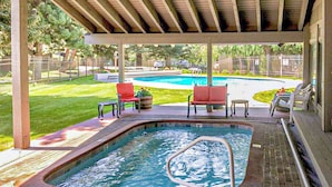 A covered outdoor swimming pool with a hot tub, surrounded by red chairs and a small table. - Sv155 - Walk to Lifts & Town - Hot Tub & Pool (Ketchum)