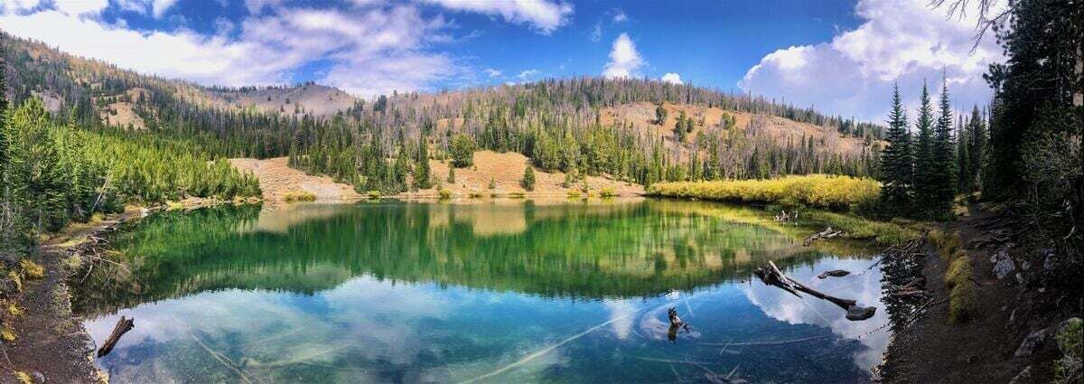 A clear mountain lake surrounded by forested hills.