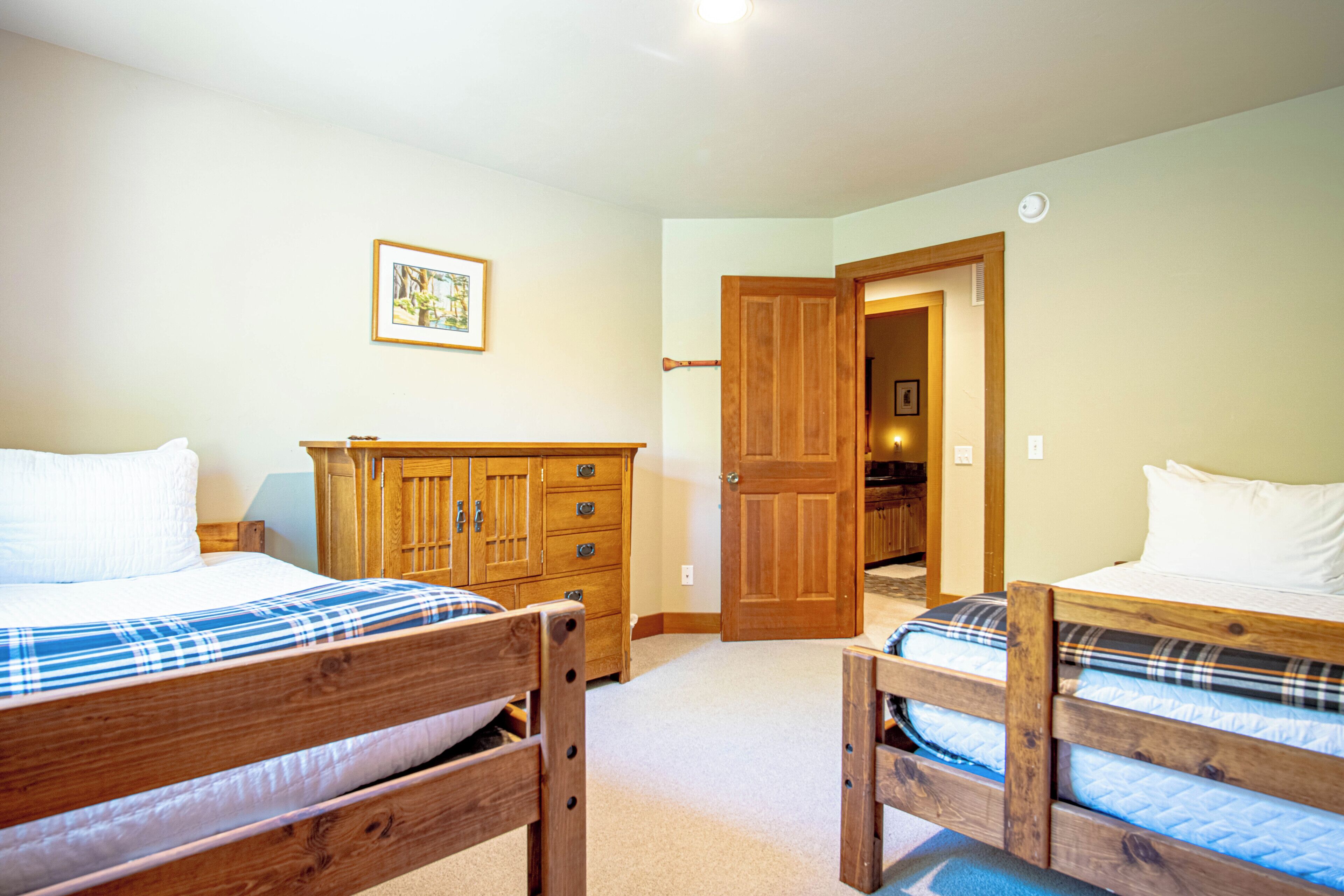 Ein Schlafzimmer mit zwei Holzbetten, einer Holzkommode und einer Tür zu einem anderen Raum.