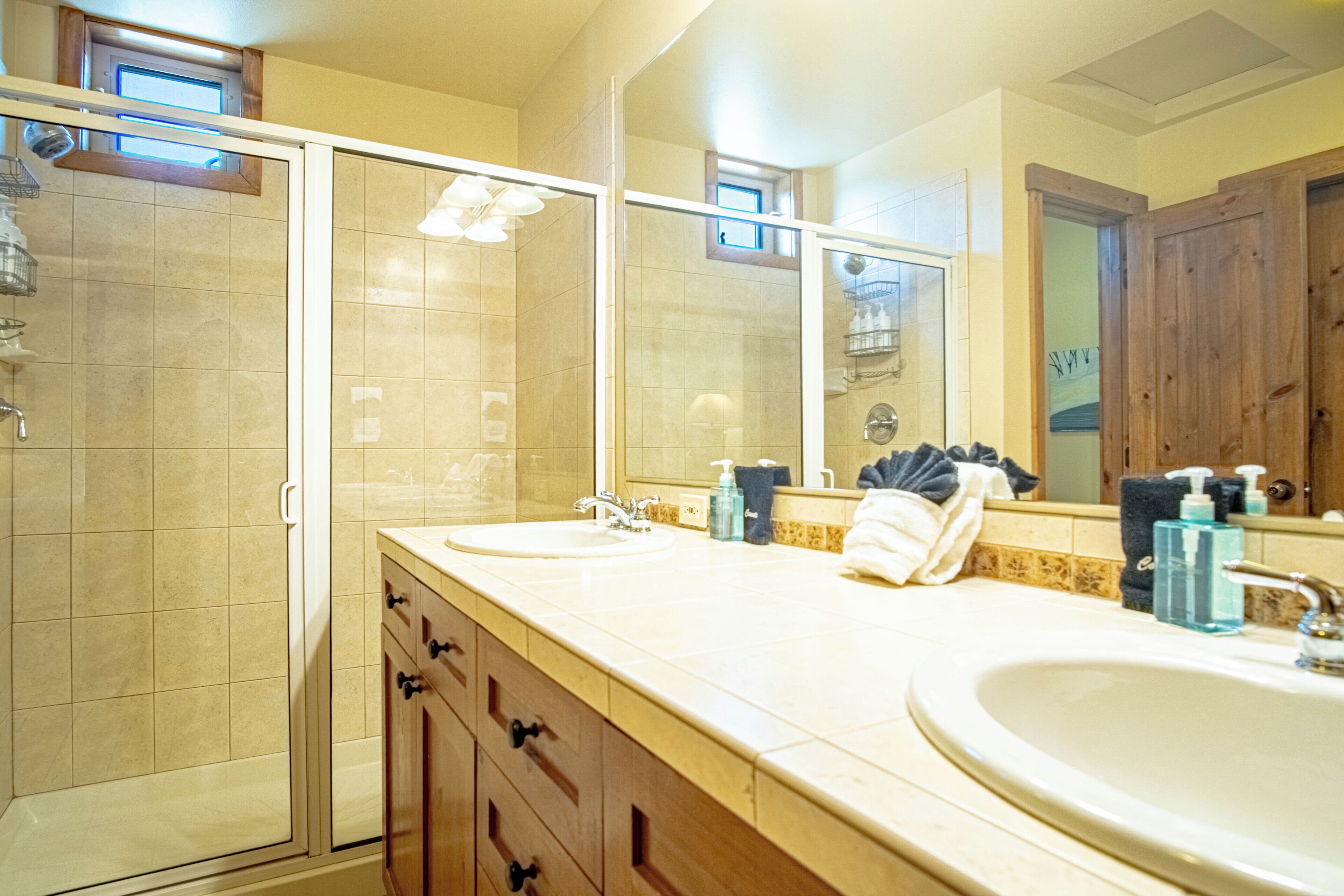 A bathroom with two sinks, a glass shower enclosure, and a large mirror.