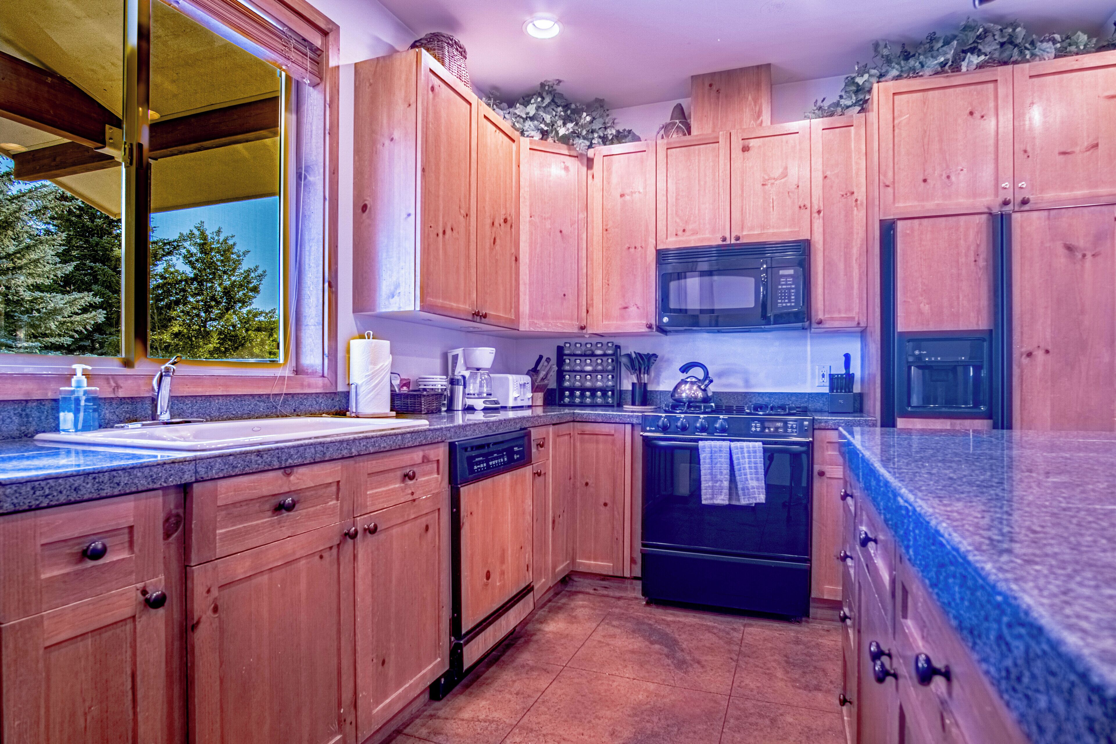 A kitchen with wooden cabinets, a microwave, a stove, and a dishwasher.