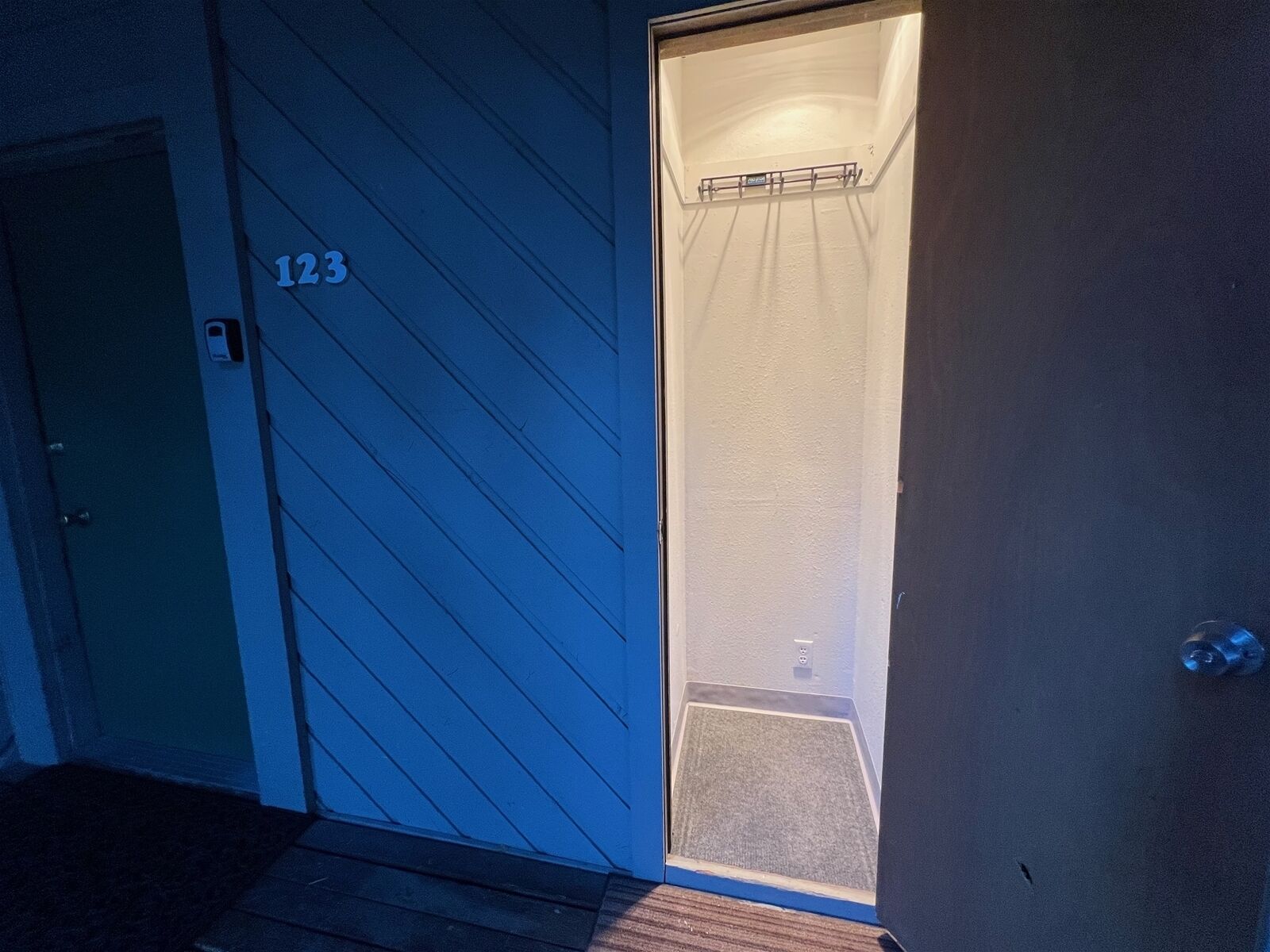 Una puerta con el número 123, un ventanal pequeño y un timbre.