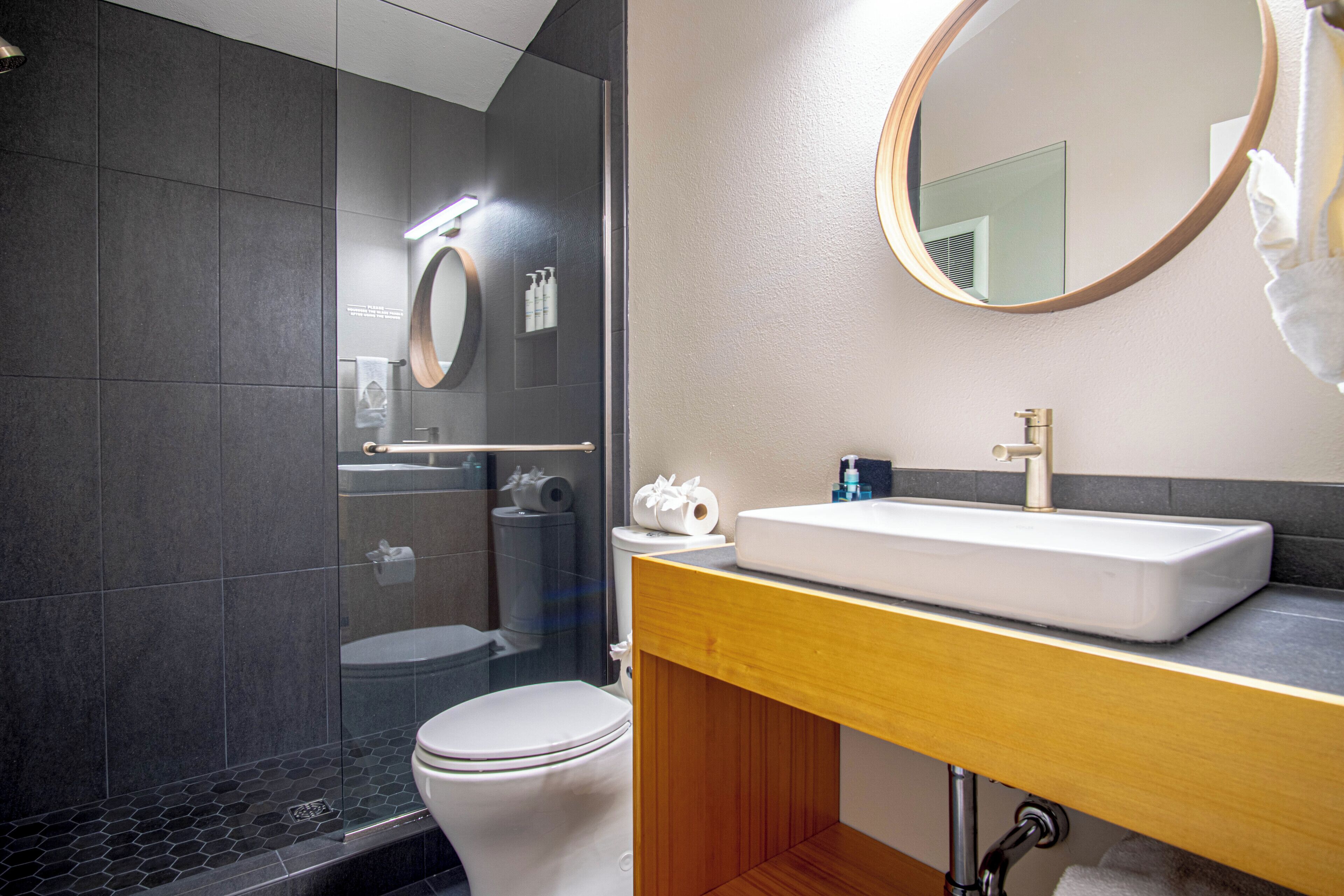A modern bathroom with a shower, toilet, and sink.