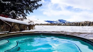 A swimming pool with clear blue water, surrounded by snow-covered ground and a view of mountains in the background. - Elkhorn Bluff Condo + Complex & Resort Amenities (Sun Valley)