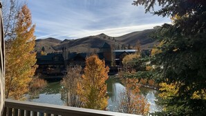 A lakeside view of a lodge with multiple buildings, surrounded by autumn foliage and hills in the background. - Bonne Vie 2233 in the Heart of Elkhorn With Resort Amenities (Sun Valley)