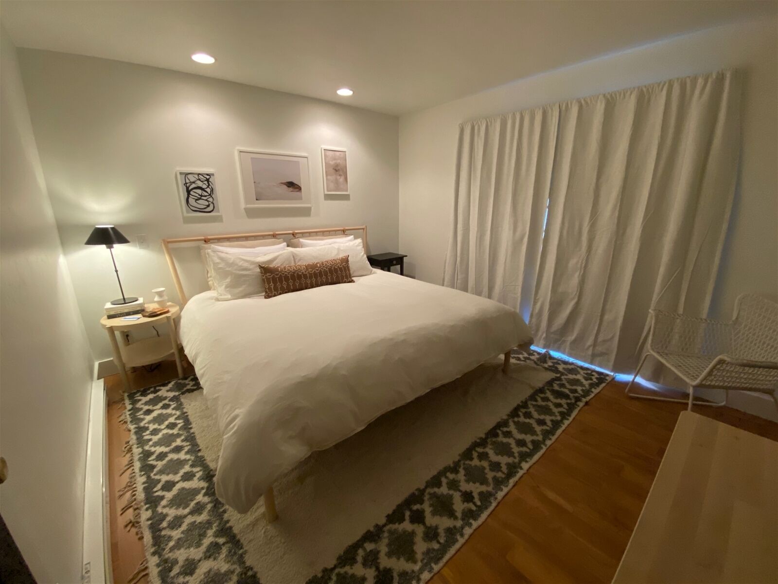 A neatly arranged bedroom with a large bed, bedside tables, a lamp, and a chair.