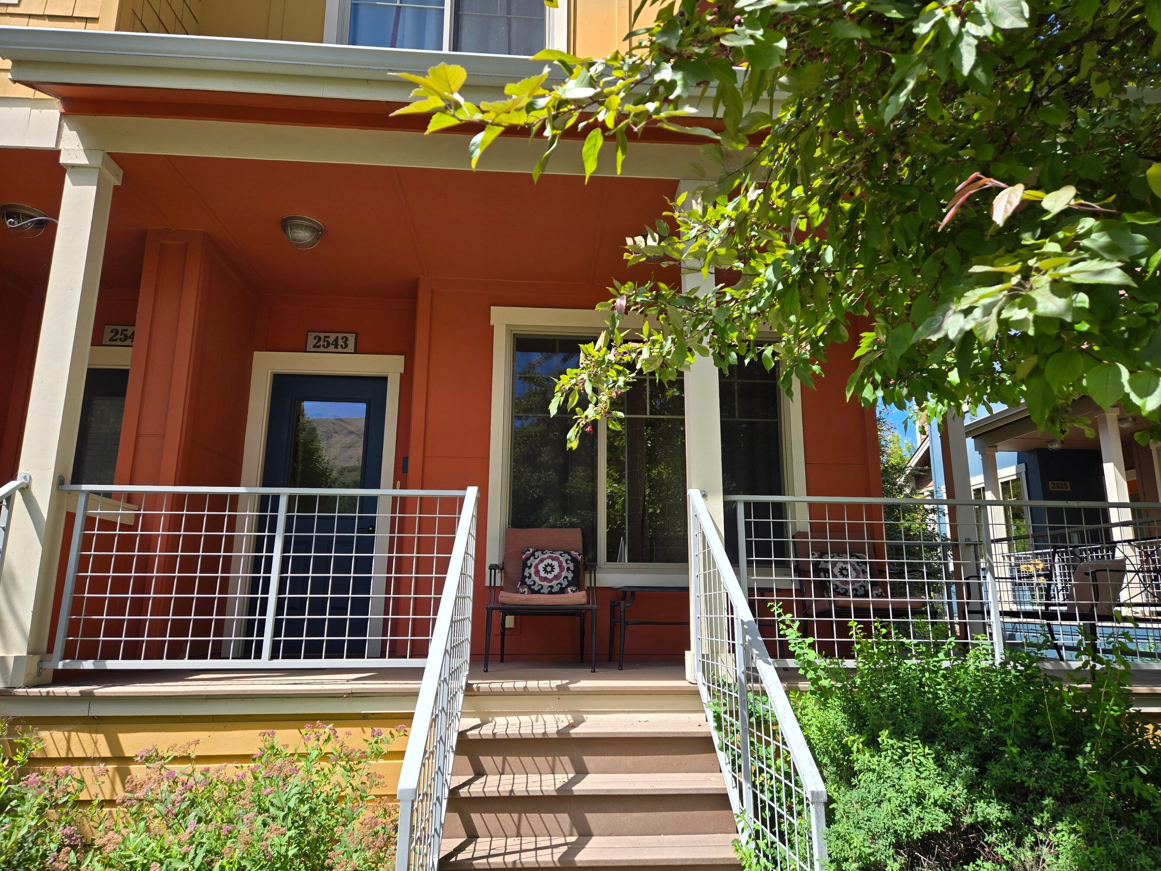 A building with a red facade, a number '2543' sign, a staircase with a railing, and a window with a view of the mountains.