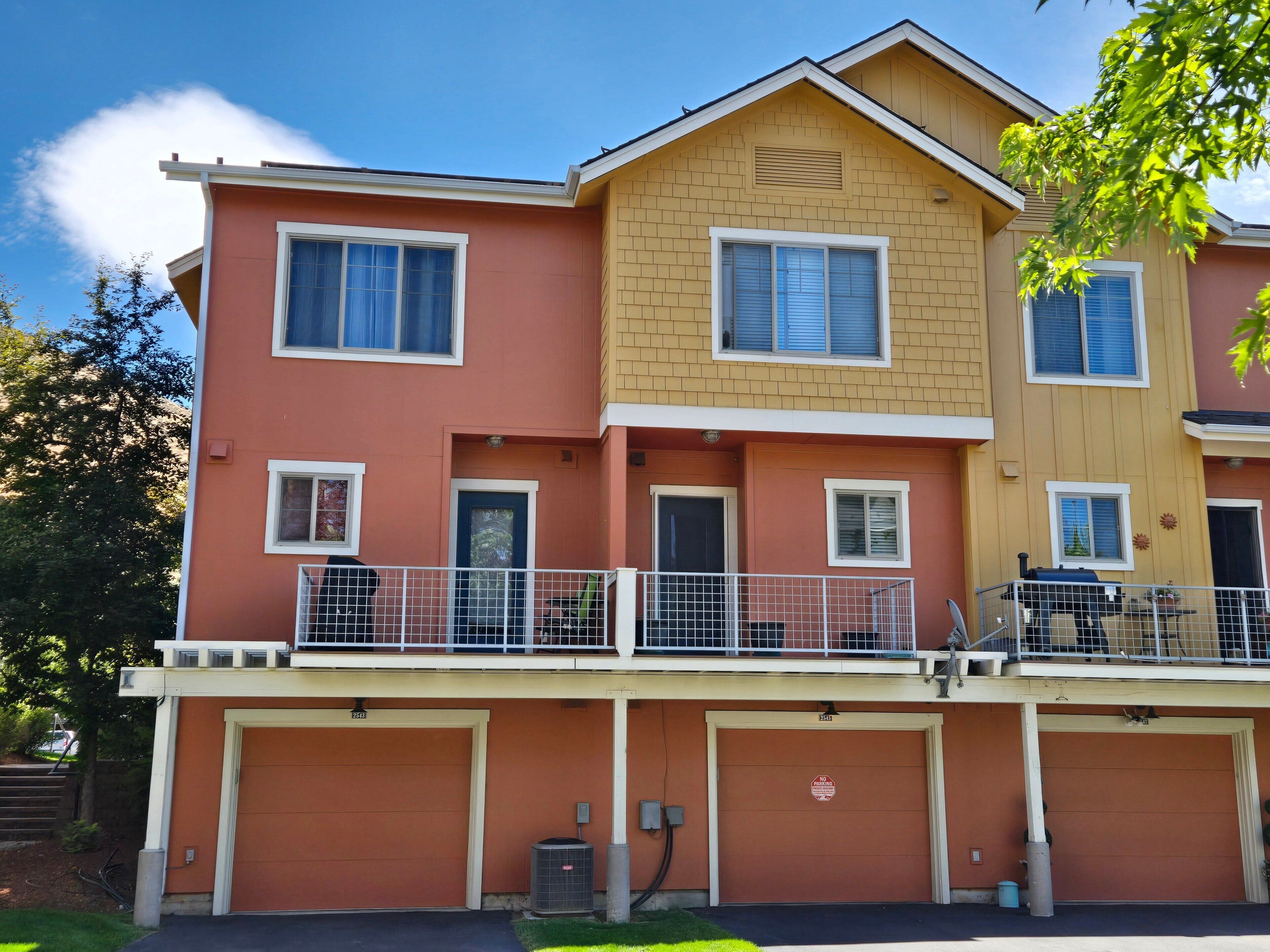 A multi-story residential building with a garage, a balcony, and a visible door.