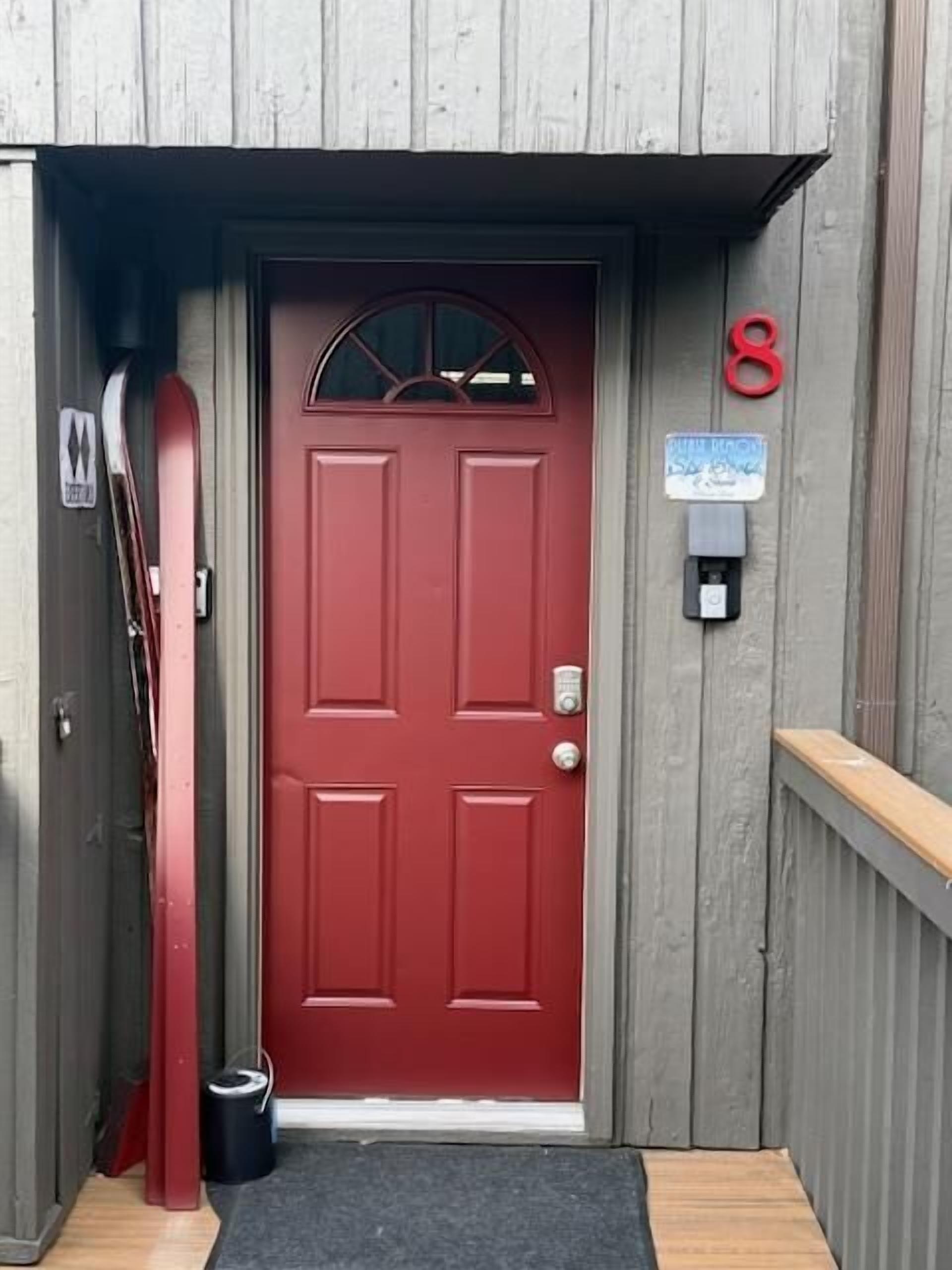 Puerta roja con un buzón y un letrero con el número 8.