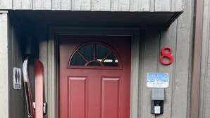 Une porte rouge avec une boîte aux lettres et un panneau portant le chiffre « 8 » au-dessus.