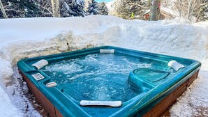 Ein Whirlpool in einer Holzeinfriedung, umgeben von Schnee.