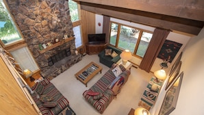 Ein gemütliches Wohnzimmer mit Kamin aus Stein, Fernseher und bequemen Sitzmöglichkeiten.