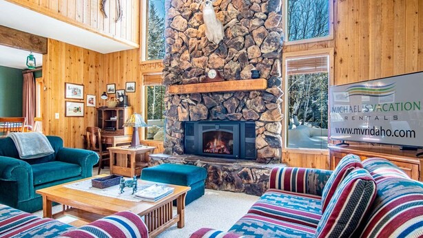 Ein gemütliches Wohnzimmer mit Kamin aus Stein, Holzwänden und bequemen Sitzmöglichkeiten.