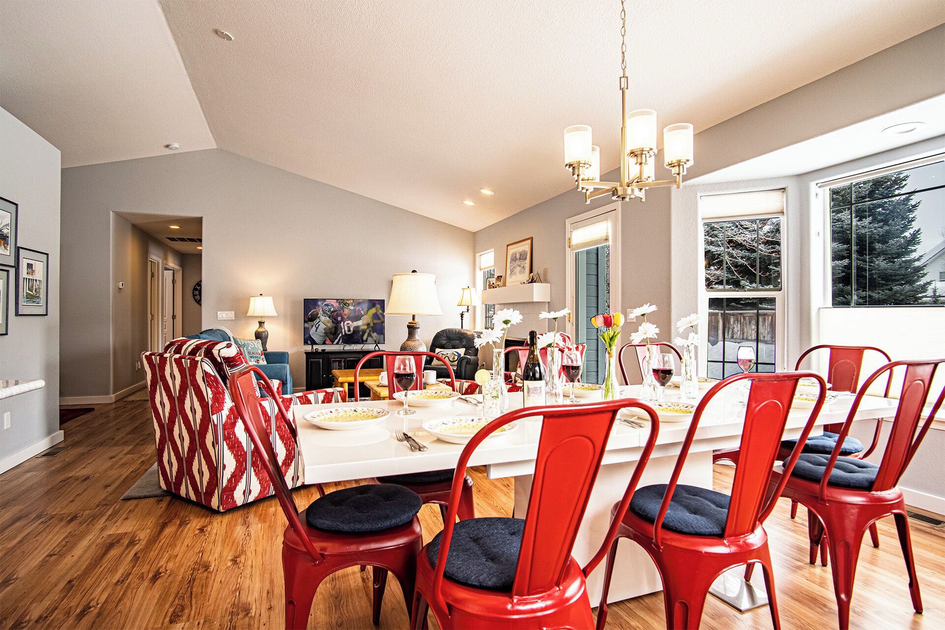A dining area with a large table, red chairs, and a chandelier.