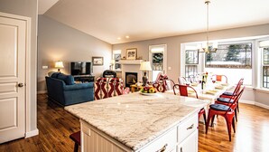A spacious living area with a fireplace, a television, and a dining area with red chairs. - In the Heart of Hailey; Private Pet-friendly 3 Bedroom Home With Garage (Hailey)