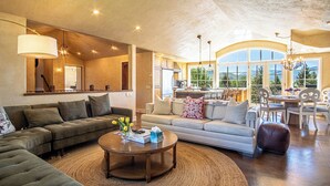 A spacious living room with a large sofa, a coffee table, and a dining area with a table and chairs. - Chateau Du Soleil- Luxury Home Near Ski Lifts & Downtown Ketchum! (Ketchum)