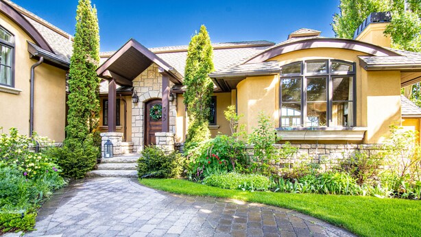 A house with a stone entrance, a curved window, and a well-maintained garden. - Chateau Du Soleil- Luxury Home Near Ski Lifts & Downtown Ketchum! (Ketchum)