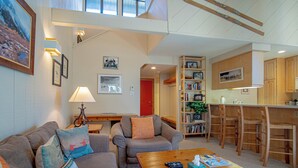 A living room with a sofa, armchair, coffee table, and a bookshelf. - Sv112 - Walk to Lifts & Town - Hot Tub & Pool (Ketchum)